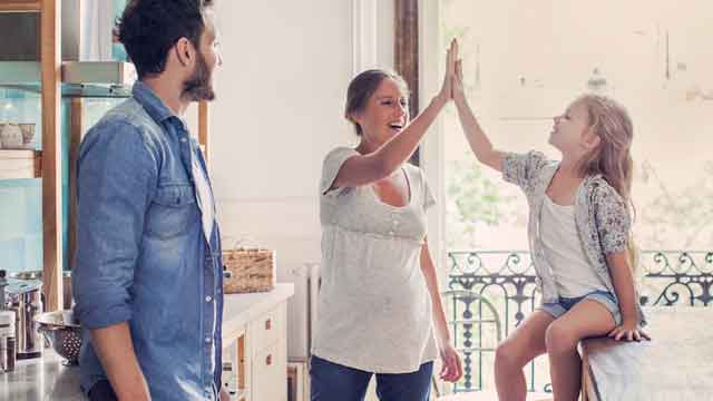 Mum and daughter doing high five in kitchen - Small