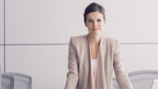 Formal business woman in an office smiling at you