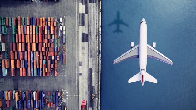 Airplane flying past containers over water