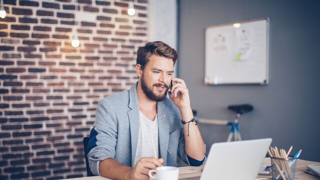 Aksjesparekonto - mann spå kontor som snakker i mobilen. 