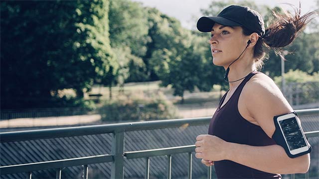 Sportswoman listening to music while jogging small