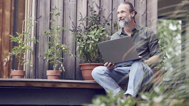 Mann som står på gaten og sjekker sin aksjebeholdning på mobilen.