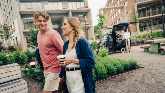 Young-woman-and-man-walking-in-park-with-coffee-small