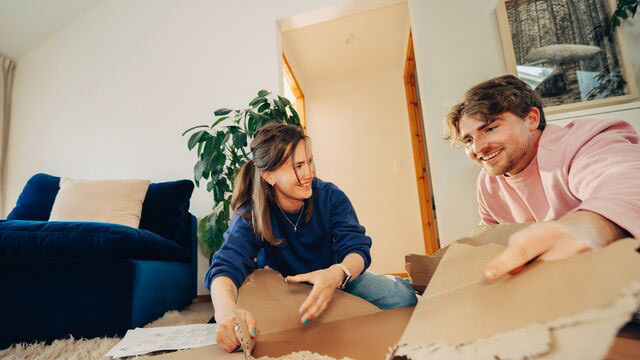 Ung kvinne sitter på stuegulvet og jobber på datamaskin