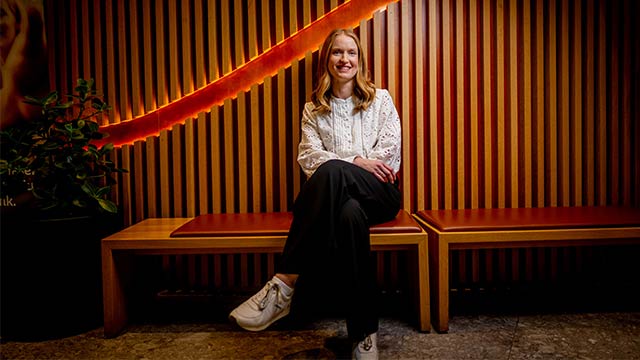 Anne Motzfeldt sitter på benk og smiler