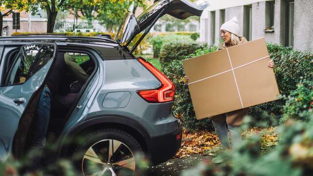 Woman placing a flat pack inside the trunk of a car SMALL